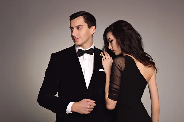 Молодая пара моды моделей в классической одежде: черный костюм и галстук, платье на белом фоне. Стиль, элегантность. Роскошь. Чувственность. Сексуальность — стоковое фото